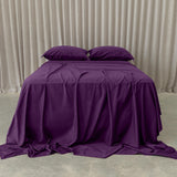 Deep purple bedding set on bed, in a neutral room.