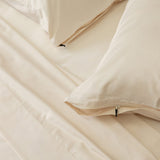 Cream bedding set with pillows on a plain background.