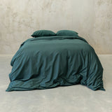 Green bedding set on a bed against a beige wall.