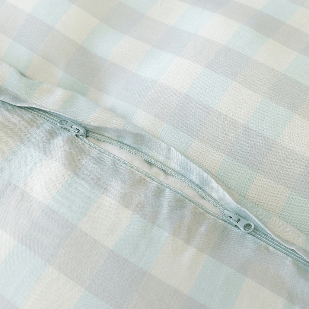 Close-up of a light blue gingham quilt cover featuring a concealed zipper closure, showcasing the secure fastening detail and soft woven fabric texture