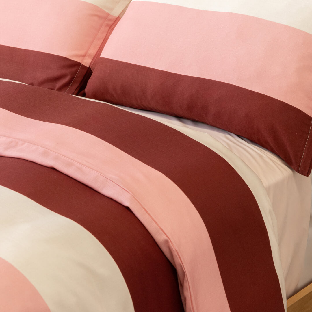Close-up of matching pillowcases and quilt cover featuring wide blush pink, cream, and burgundy stripes, showcasing the coordinated bedding design and smooth finish.