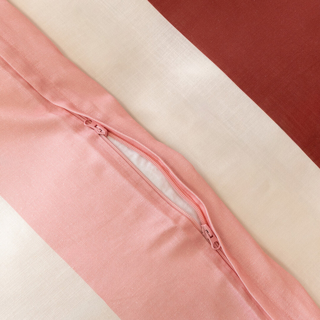 Close-up of a striped quilt cover featuring a concealed zipper closure, highlighting the secure fastening detail and soft woven fabric in pink, cream, and burgundy tones.