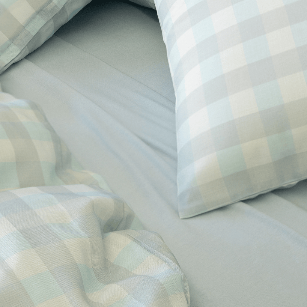 Light blue gingham quilt cover and pillowcases paired with a matching blue fitted sheet, showcasing the soft fabric texture and coordinated bedding design.