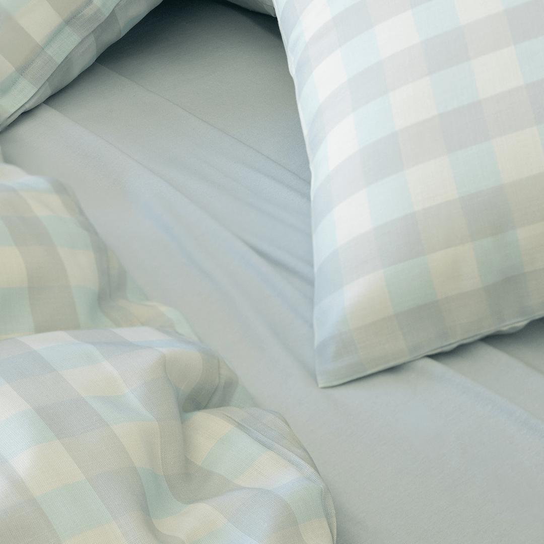 Light blue gingham quilt cover and pillowcases paired with a matching blue fitted sheet, showcasing the soft fabric texture and coordinated bedding design.
