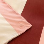 Close-up of a quilt cover corner tie detail in blush pink fabric, designed to help keep the quilt insert securely in place inside the cover.