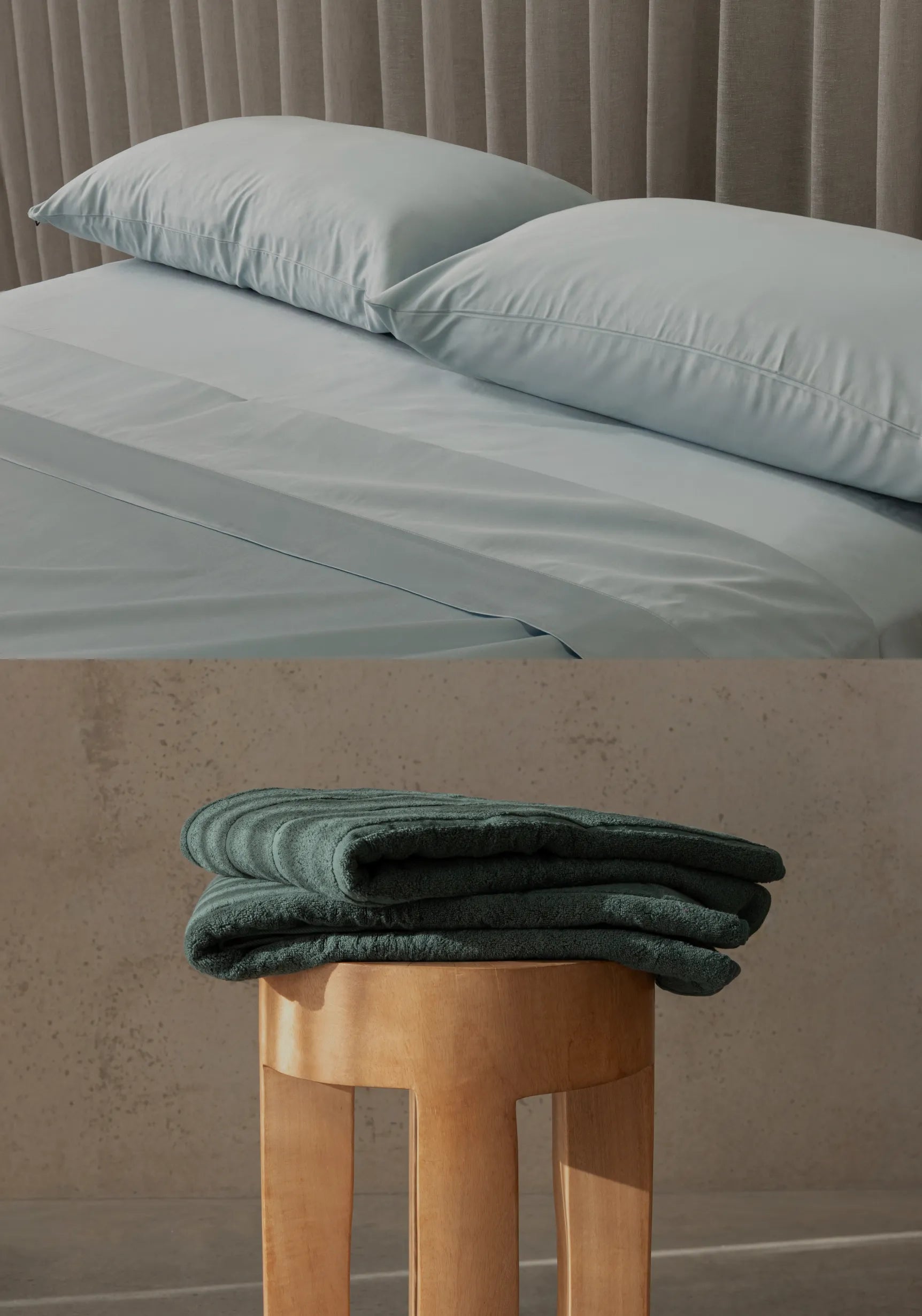 Light blue bedding set on a bed with a green folded towel on a wooden stool below.