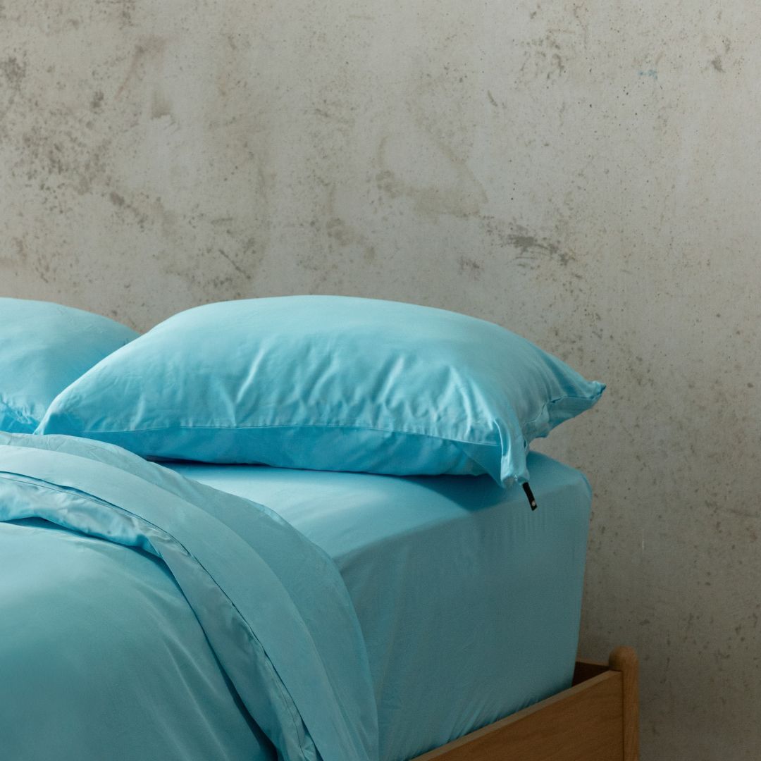 Light Blue bedding set on a bed against a textured wall.