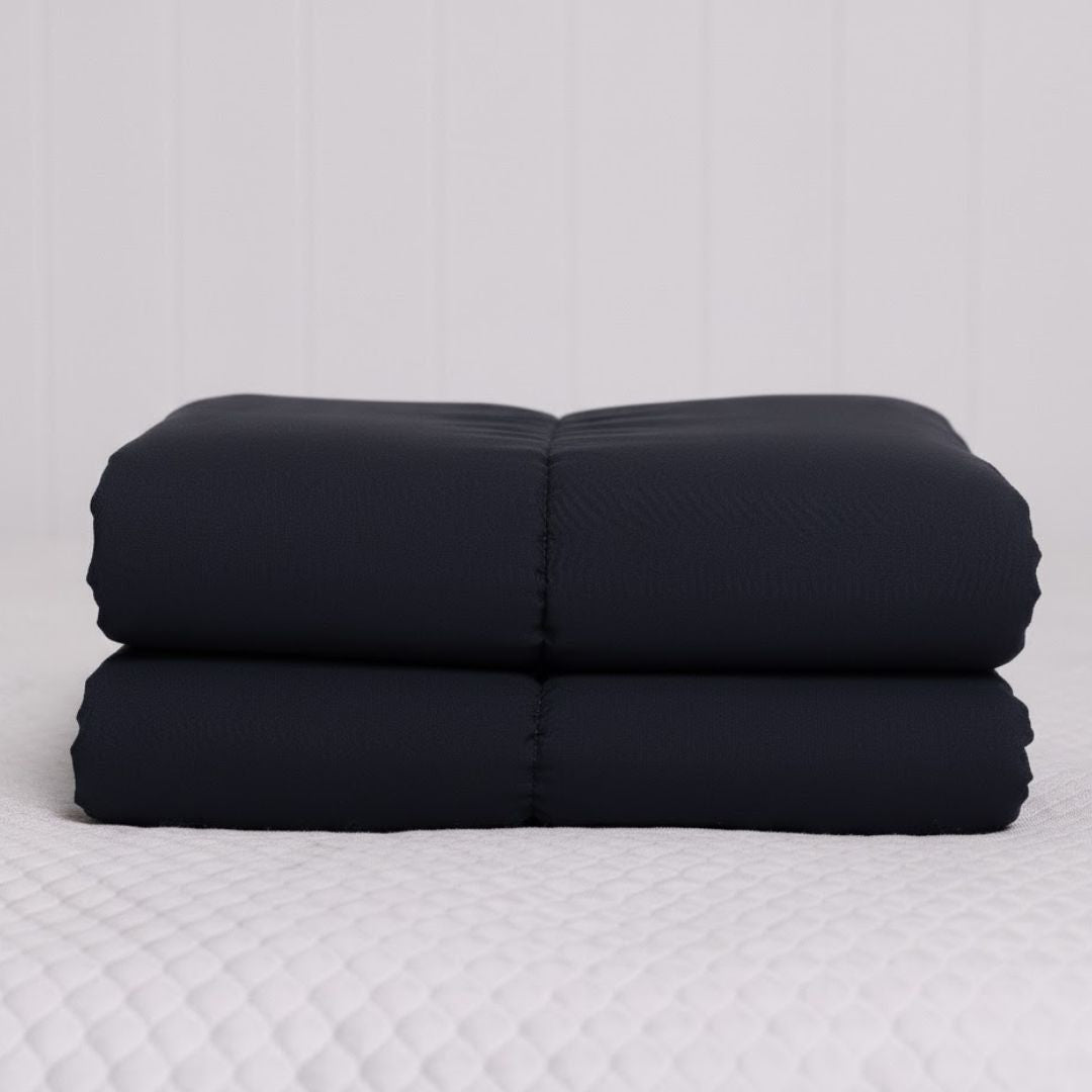Stack of black cooling blankets on a white surface
