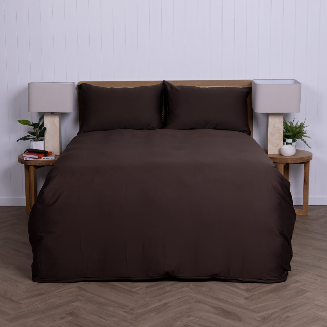 Brown bedspread set on a bed with matching pillows against a white wall.