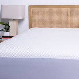 Bed with white mattress protector and wooden headboard in a bedroom setting.