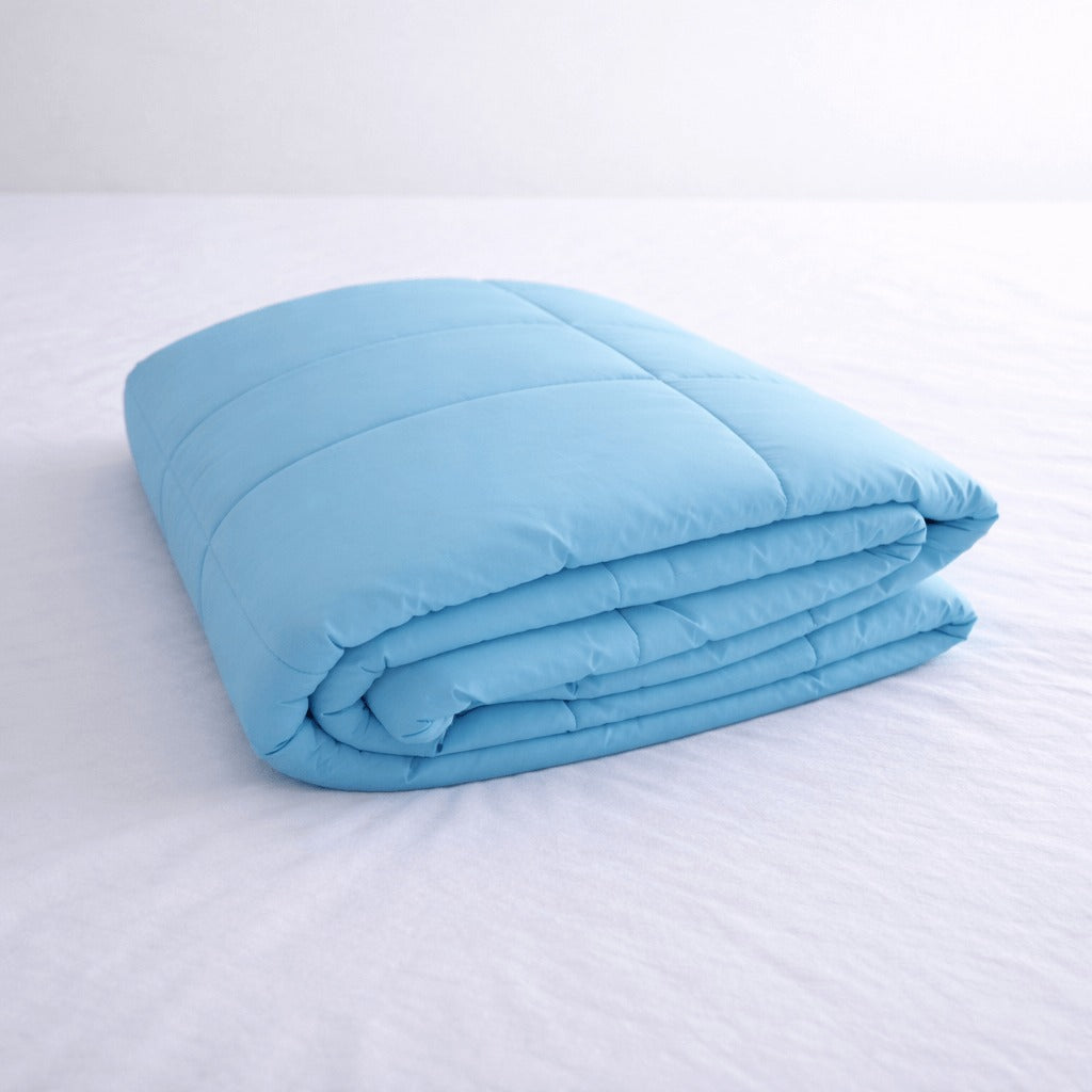 Folded light blue cooling blanket on a white bed.