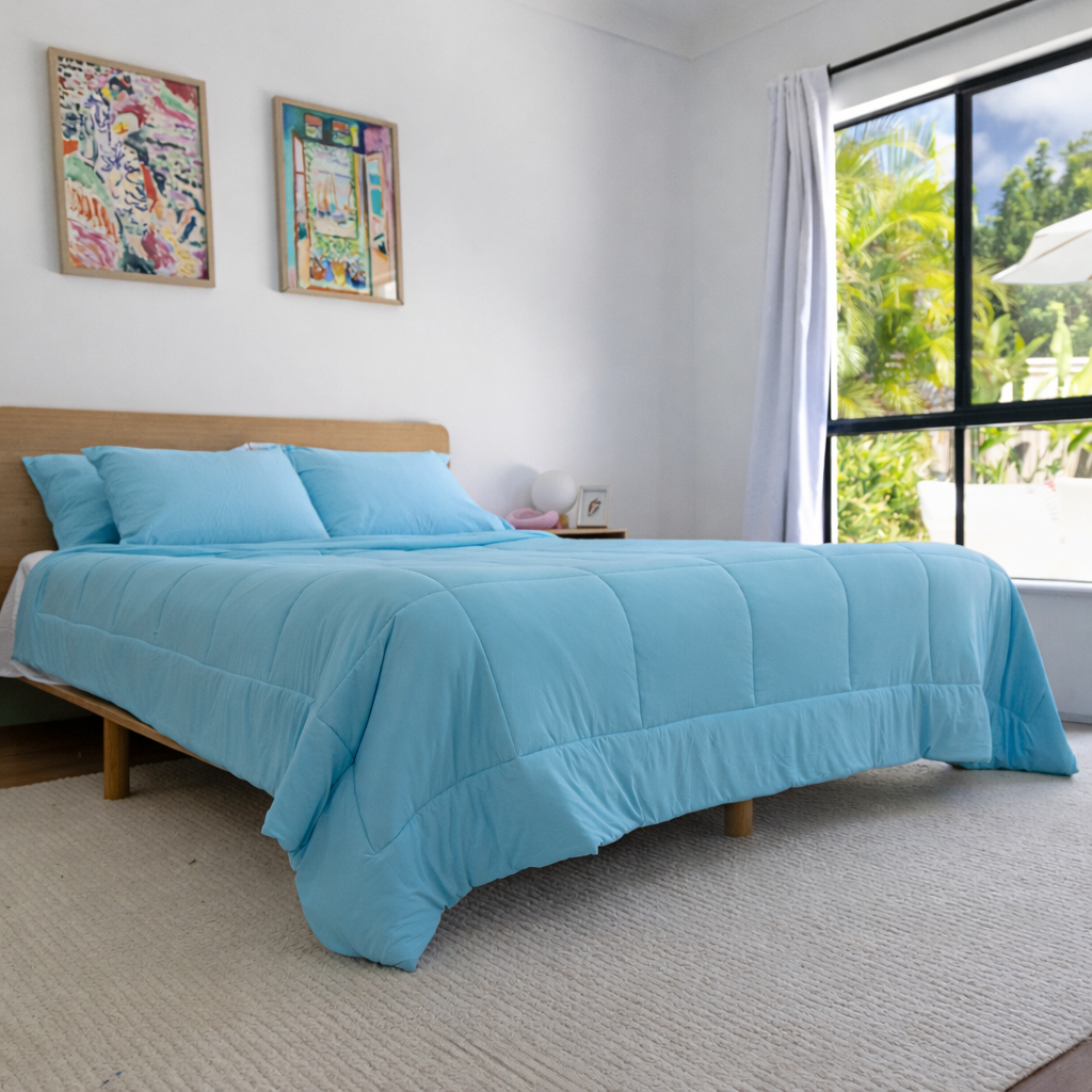Bedroom with a bed covered in a blue comforter and pillows, large window with view of greenery.