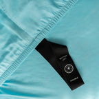 Close-up of a blue fabric with a black label on a light blue background