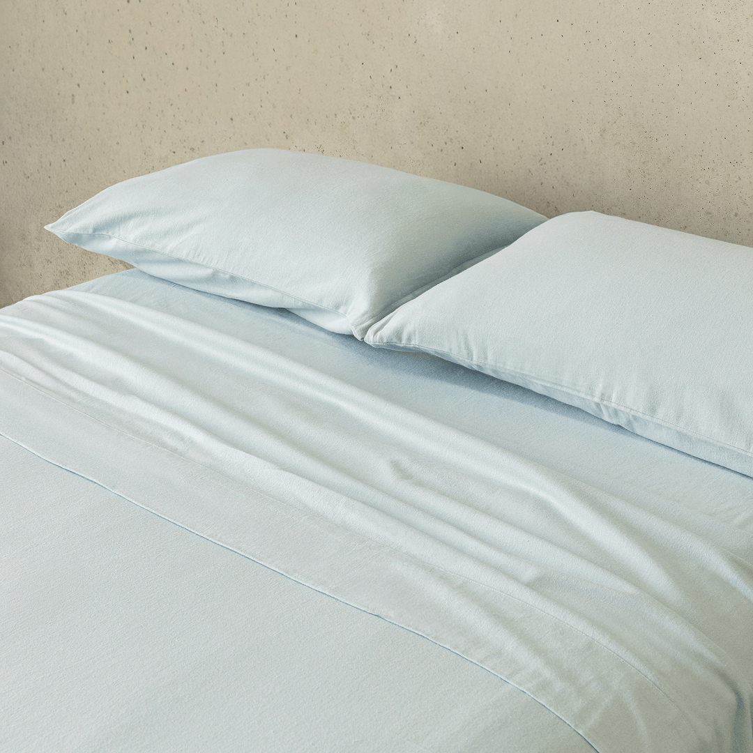 Close-up of a light blue fitted sheet and matching pillowcases, highlighting the smooth texture, soft finish, and coordinated bedding design.