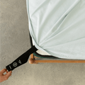 Light blue fitted sheet with an orientation tag pulled from the mattress corner, demonstrating the easy-to-identify labeling system for quick bed setup.