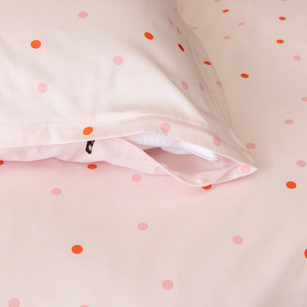 Close-up of a pink quilt cover with orange polka dots, and the matching pillowcase with an invisible zipper.