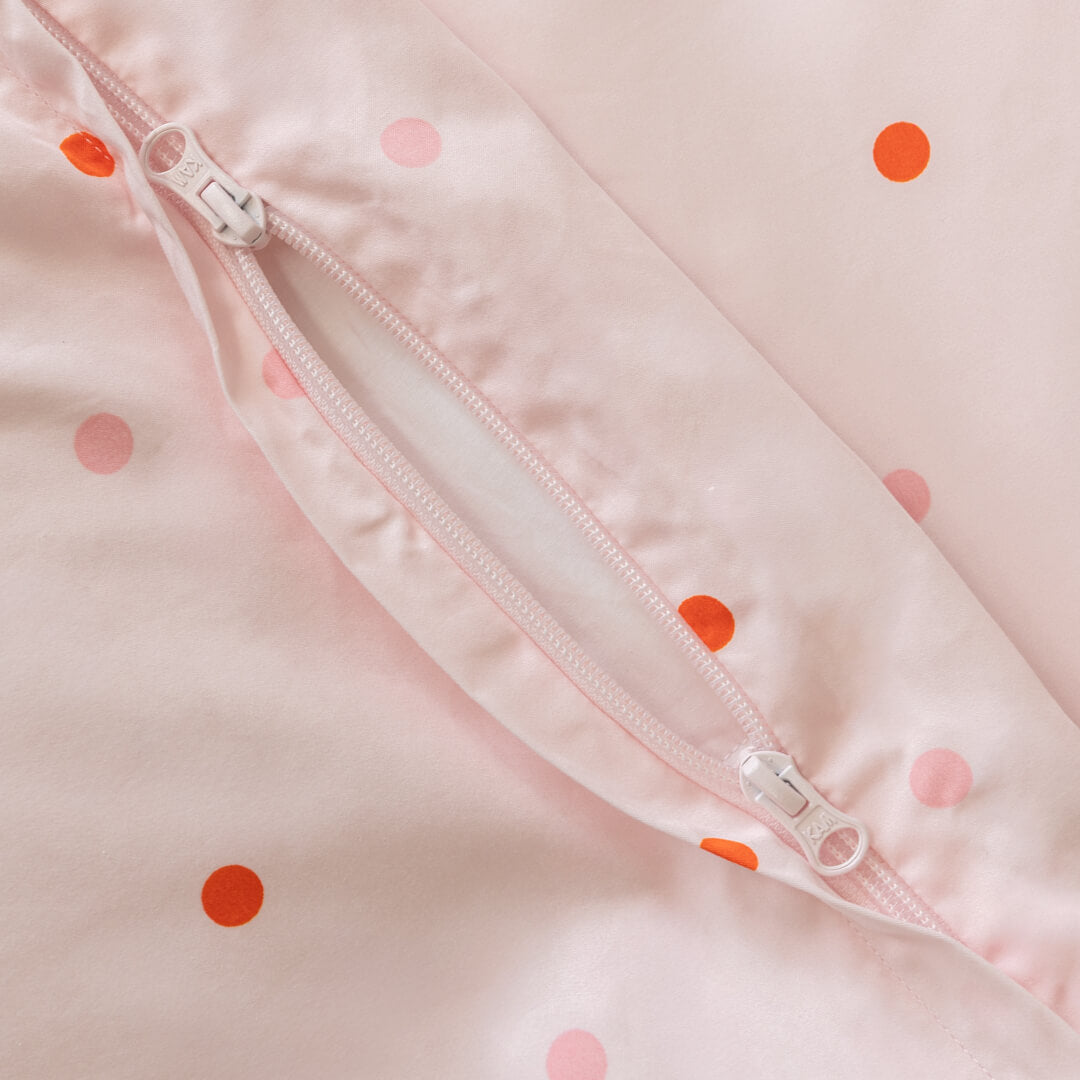 Close-up of a pink and orange polka dot quilt cover zipper.