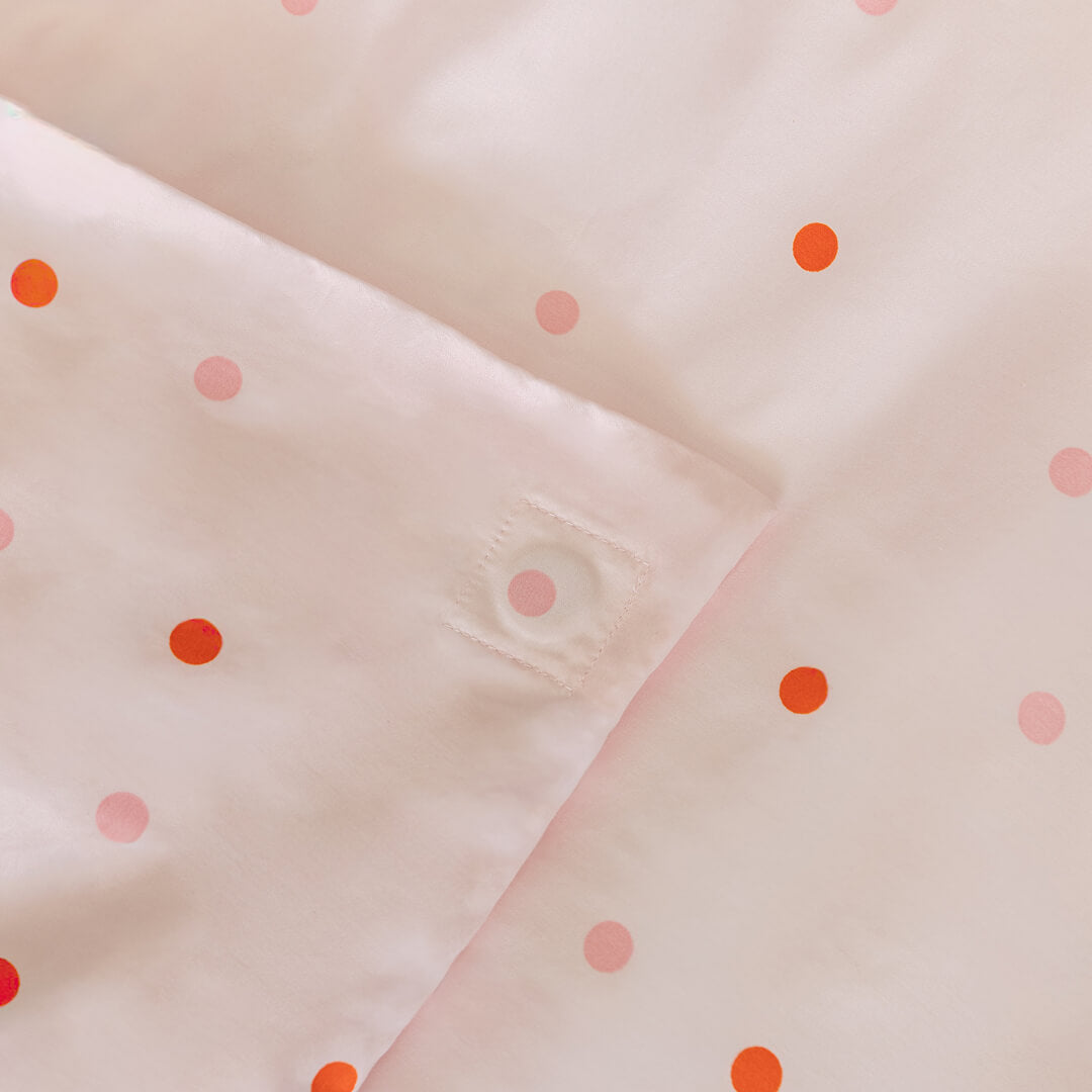 Close-up of quilt cover magnetic corner with pink polka dots on a matching fabric background.