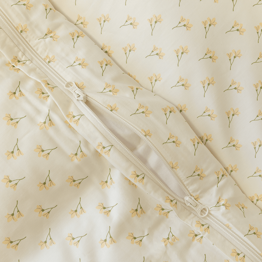 Close-up detail of a cream floral print quilt cover with an open zipper closure