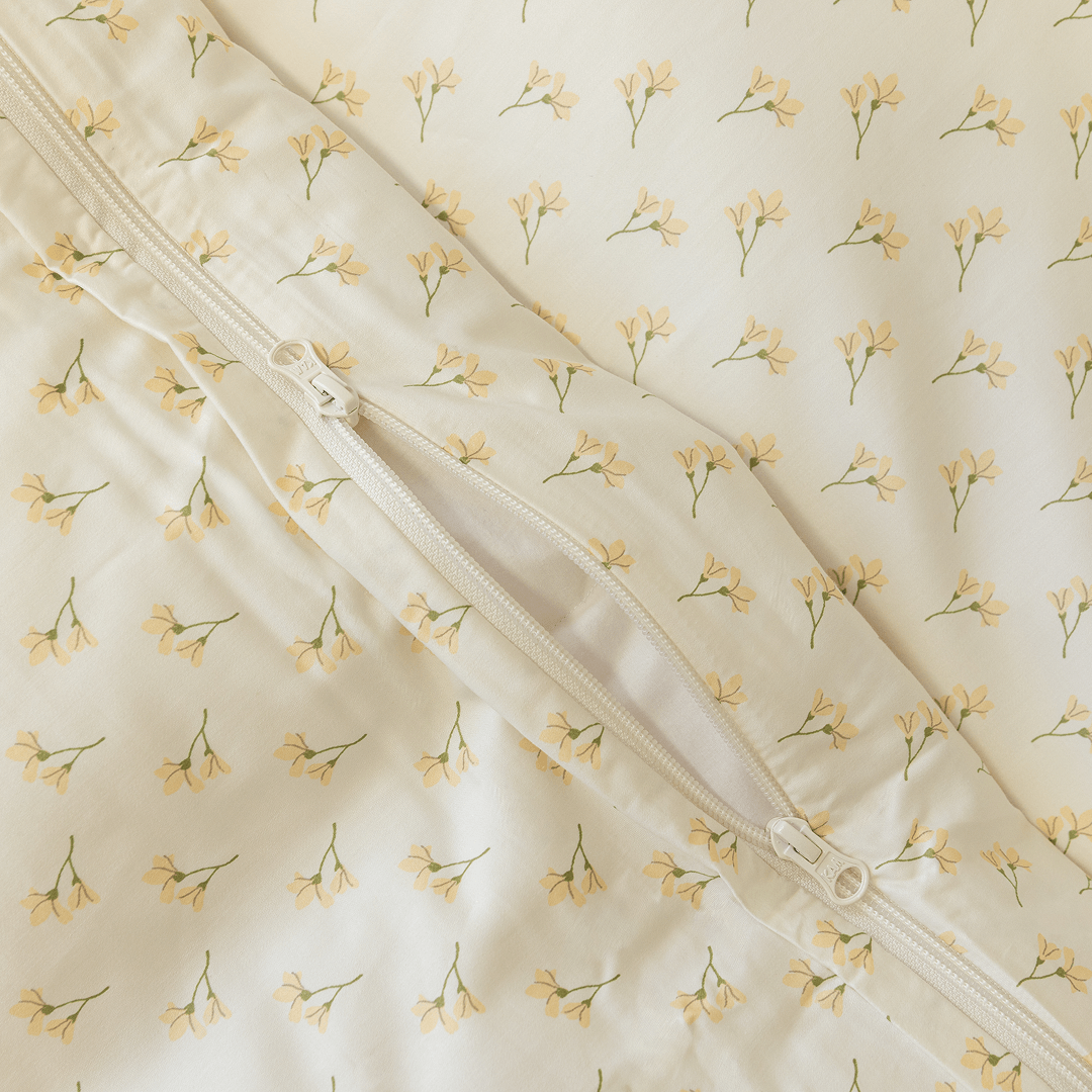 Close-up detail of a cream floral print quilt cover with an open zipper closure