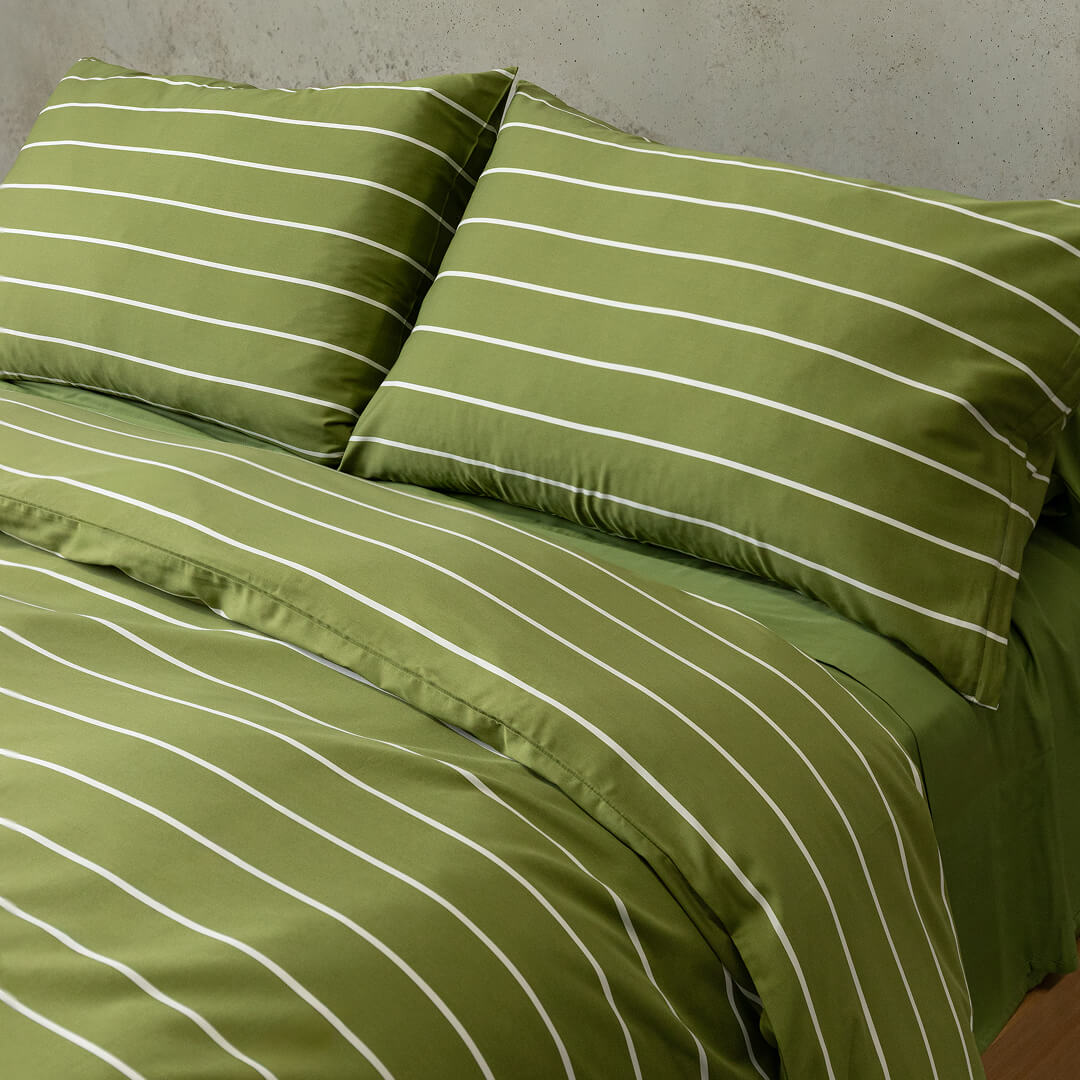 Green striped bedding set on a bed with a neutral background.