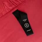 Close-up of a red fabric with a black labelled corner loop strap showing. 