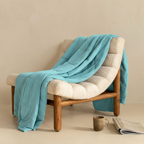 Bright light blue cooling blanket draped on a modern chair. 