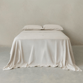 Beige fitted sheet set styled on a neatly made bed with matching pillowcases, featuring a warm neutral tone, soft drape, and minimalist bedroom aesthetic.