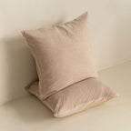 Two beige textured pillows on a light surface with a neutral background.