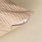 Textured beige pillow with a zipper on a beige background.