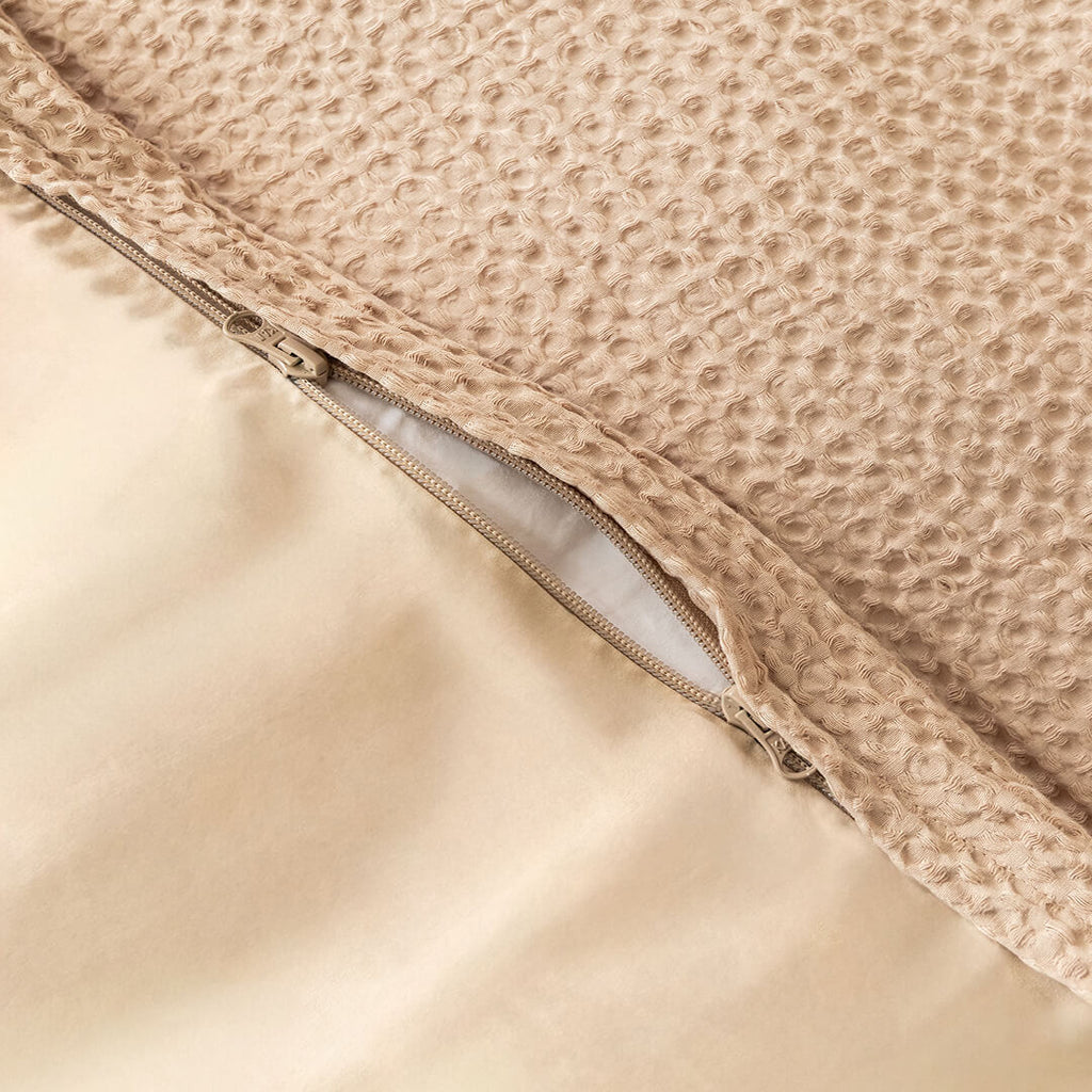 Close-up of a textured beige fabric with a zipper.