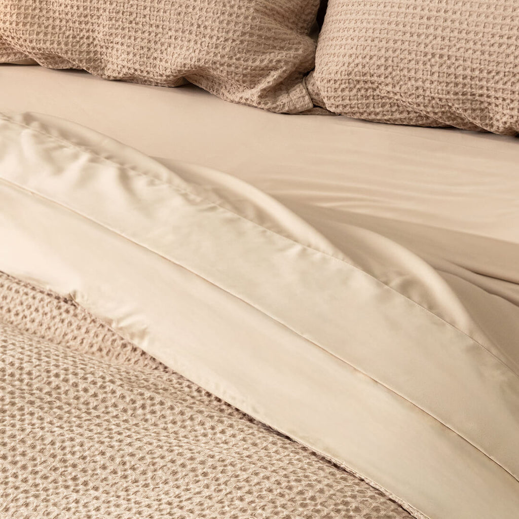 Close-up of beige bedding with textured pillows.