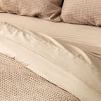 Close-up of beige bedding with textured pillows.