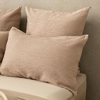 Waffle textured beige pillows on a neutral background.