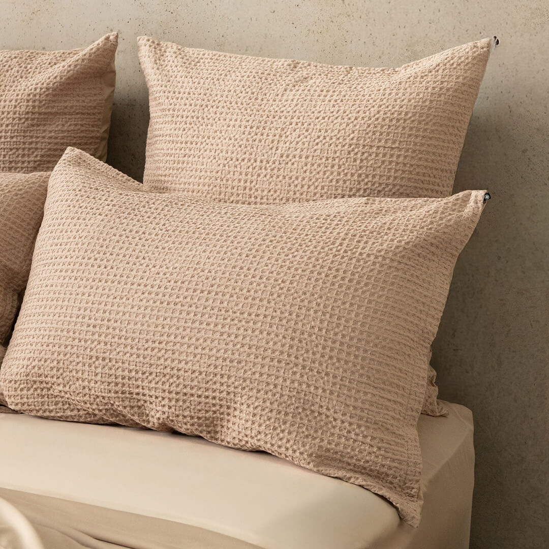 Waffle textured beige pillows on a neutral background.