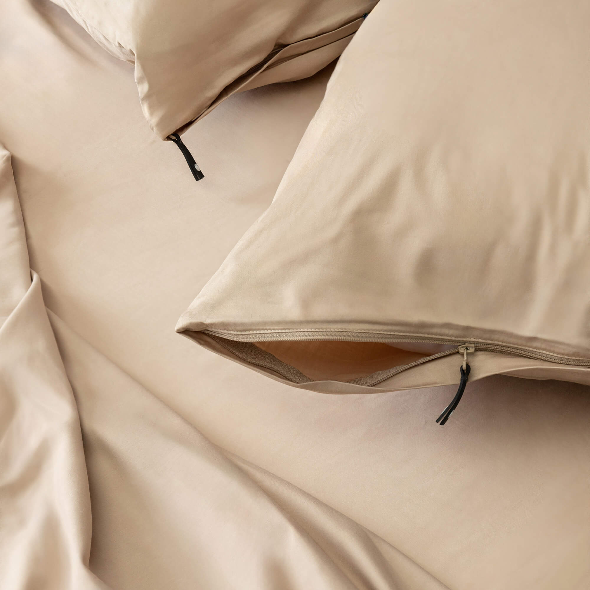 Close-up on beige coloured invisible-zip pillowcases, on the bed.