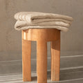 Beige bath towel folded on stool