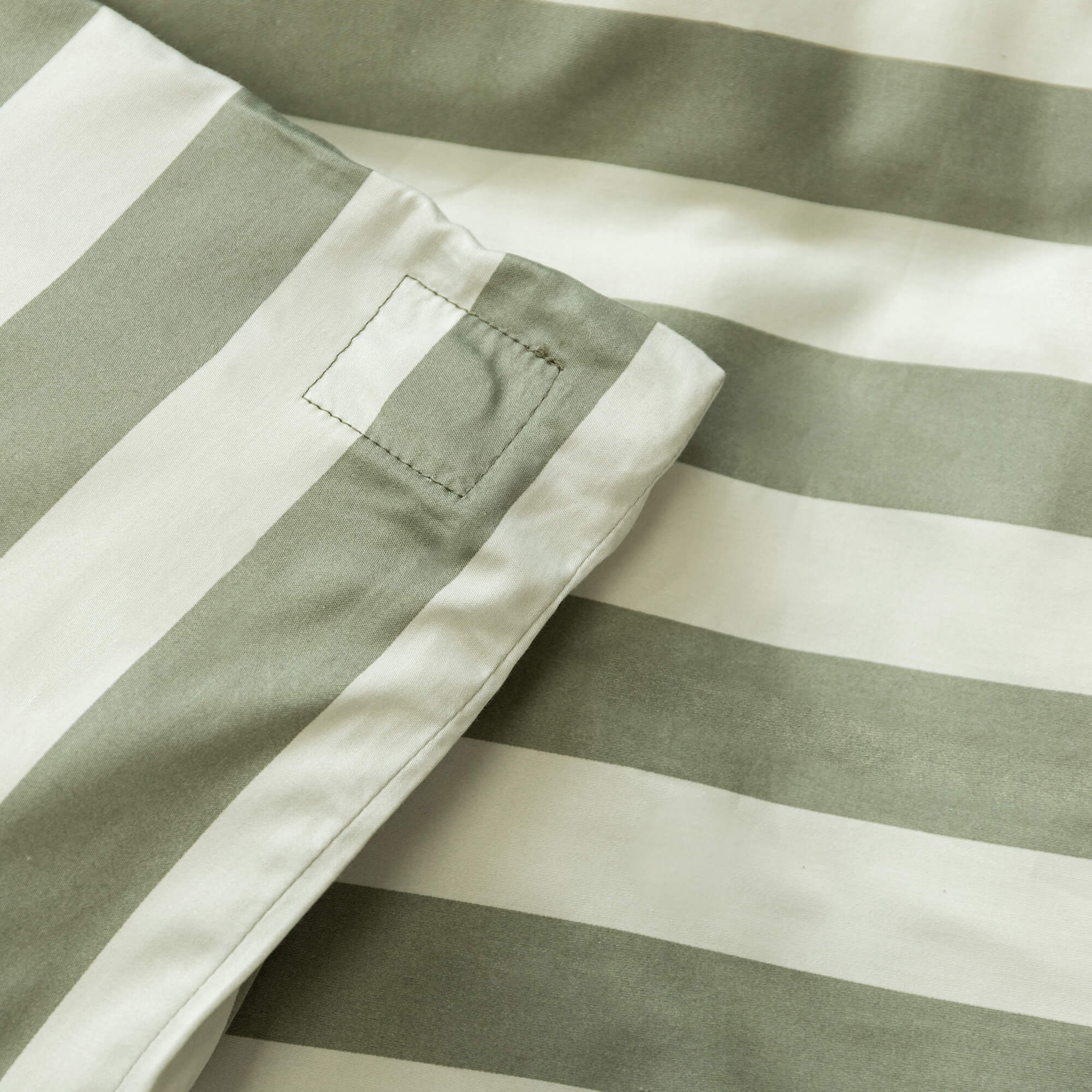Close up of a sage green and light green stripe quilt cover magnetic corner. 
