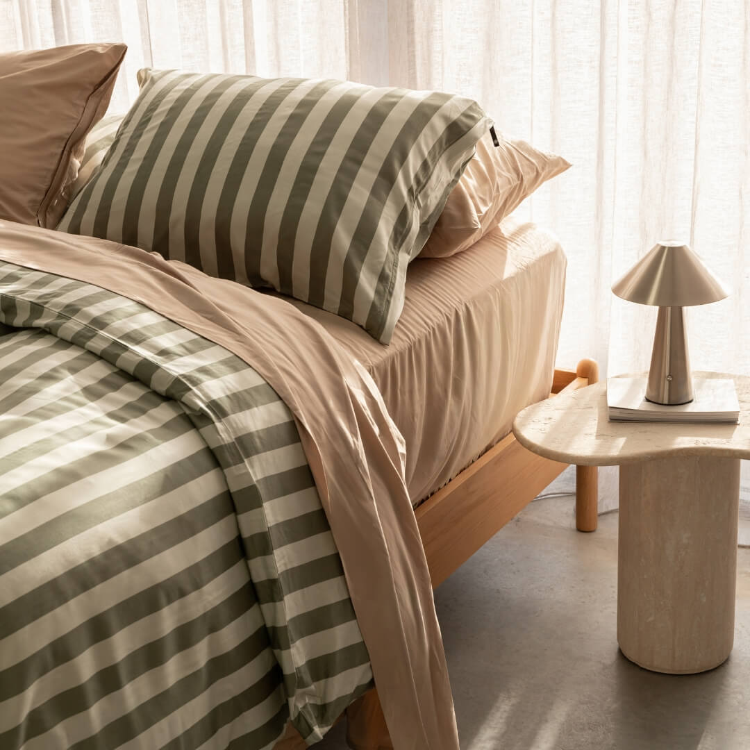 Daintree stripe quilt cover paired with coral bed bedding set, against a beige curtain backdrop. A marble bed side table and lamp featured in the corner.