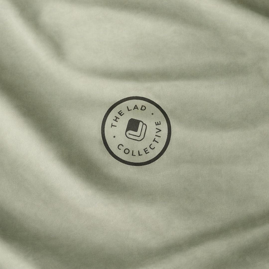 Close-up of a light green fabric with 'The Lad Collective' logo.