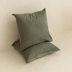 Two green textured European pillows on a beige surface.