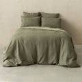 Green textured bedding set on a bed against a beige wall.