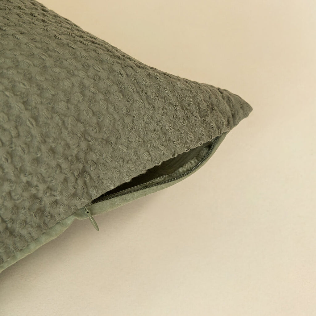 Textured green pillow on a beige background, highlighting the invisible zip. 