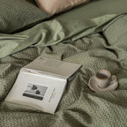 Book and cup on a textured green waffle quilt cover.