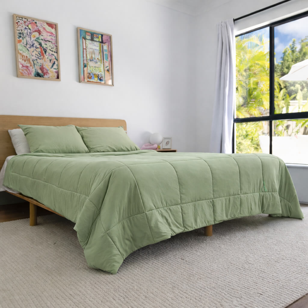 Bedroom with a bed covered in green bedding and two colorful paintings on the wall.