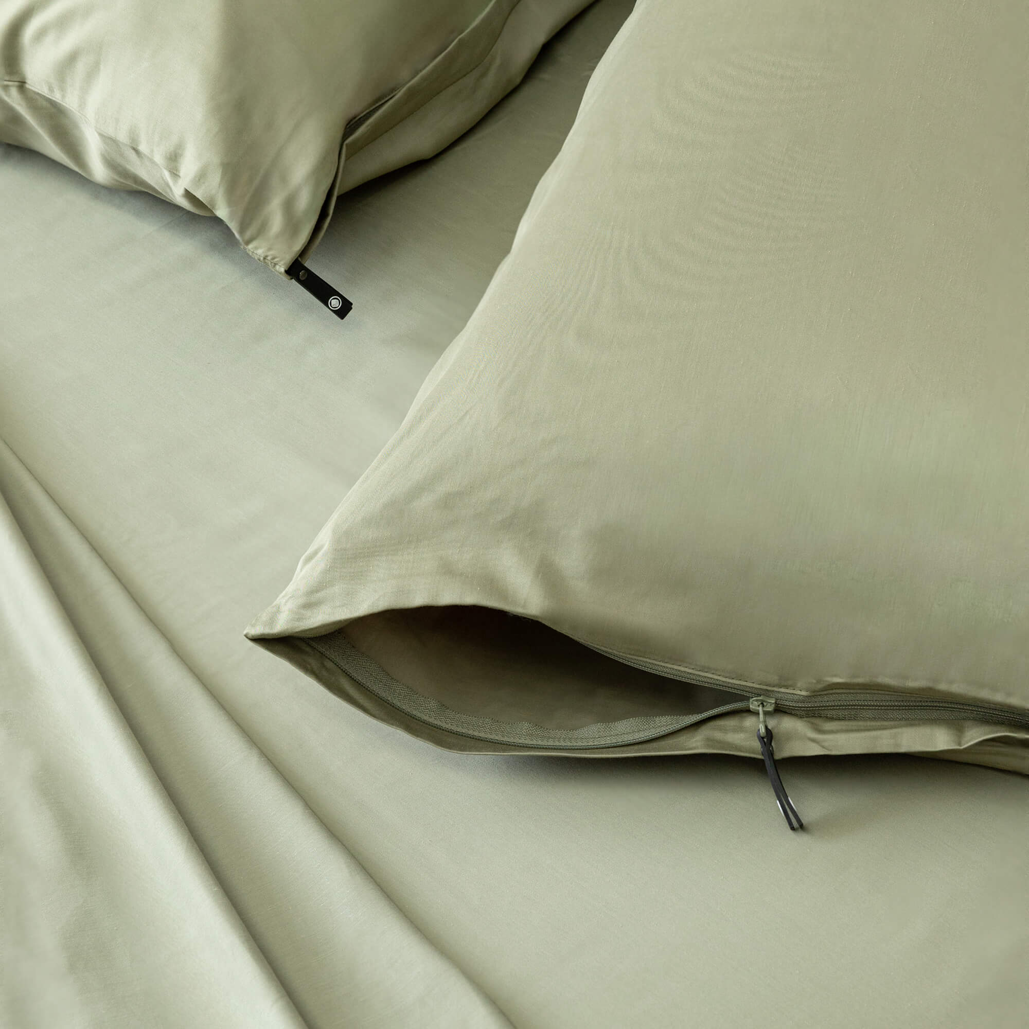 Sage green invisible-zip pillowcases close-up.