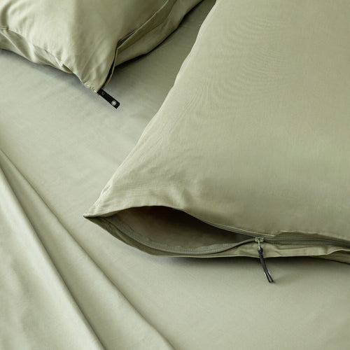 Close-up of green bedding with a zipper on pillowcases.