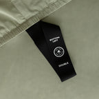 Close up of labelled corner loop strap on sage green fitted sheet that reads 'Bottom Left' and 'Double'.