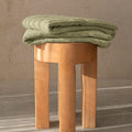 Sage bath towel folded on stool