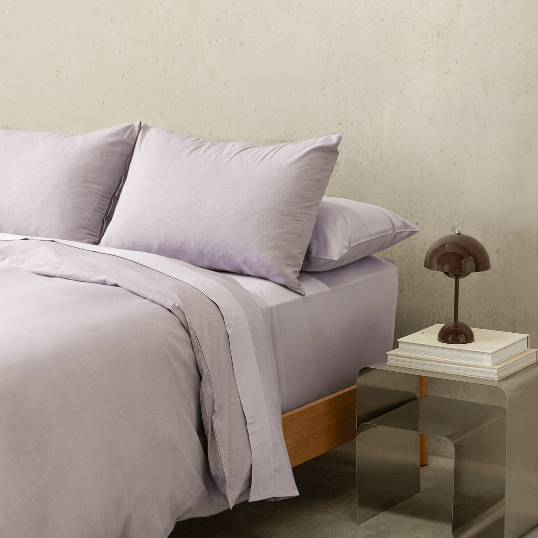 Angled view of the Daylesford lilac quilt cover set with matching pillowcases on a modern bed.